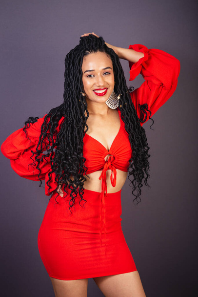 Beautiful black Brazilian woman, dressed in red. Half body portrait, gray infinity background. - Фото, изображение