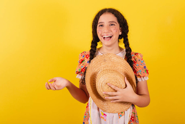 Girl wearing traditional orange clothes for festa junina. Greeting and smiling wearing hat. - Foto, Bild