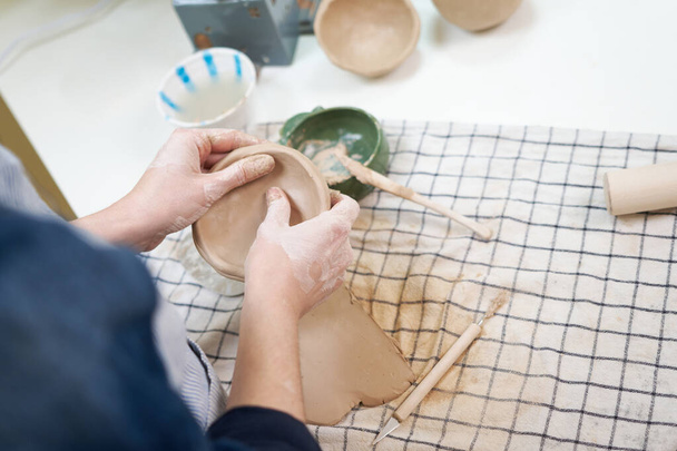 woman forming clay pot shape by hands, closeup in artistic studio. - 写真・画像