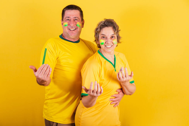 adult couple, soccer fans from Brazil, calling with their hands, welcome, inviting. - Foto, Imagen
