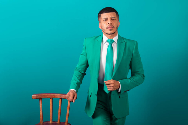 Brazilian black man, dressed in suit and green tie, Businessman. posing with wooden bench - Φωτογραφία, εικόνα