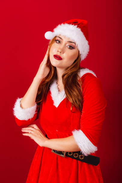 красивая бразильская рыжая женщина, одетая в рождественскую одежду, Санта Клаус. вертикальные крупным планом снимки лица, моделирование для камеры. - Фото, изображение