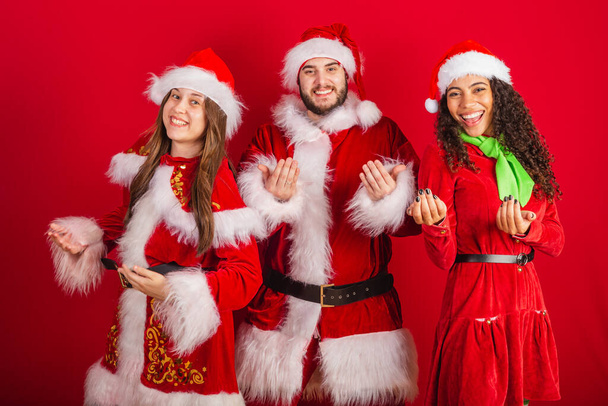 brazilian friends with christmas clothes, santa claus. inviting hands. - Foto, imagen