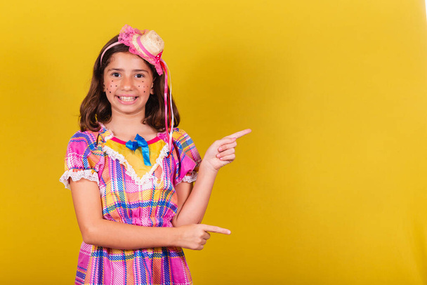 brazilian, caucasian child, festa junina clothes, pointing with finger to negative space, text, advertisement, advertisement. May, June and July festivities, festa junina celebrations - Photo, image