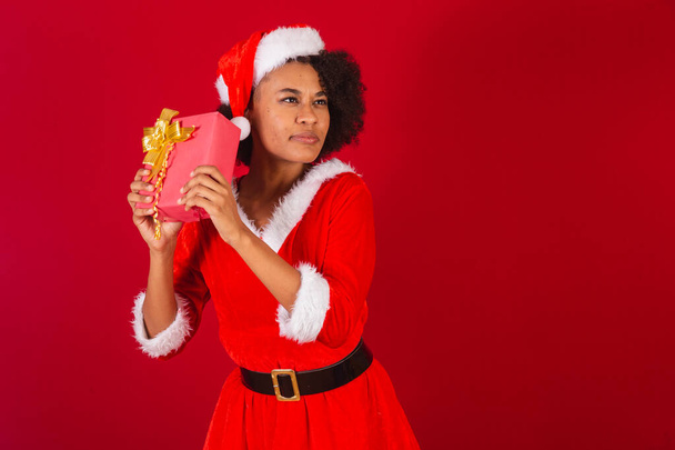 beautiful black brazilian woman, dressed as santa claus, mama claus, finding out what is red gift - 写真・画像