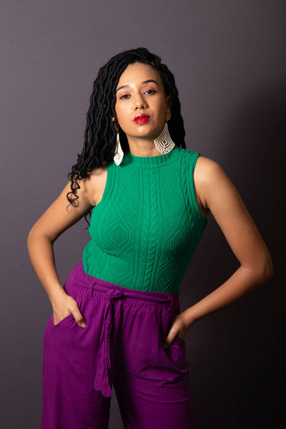 Beautiful Brazilian black woman, dressed in green and purple. Half body portrait, gray infinity background. - Fotoğraf, Görsel