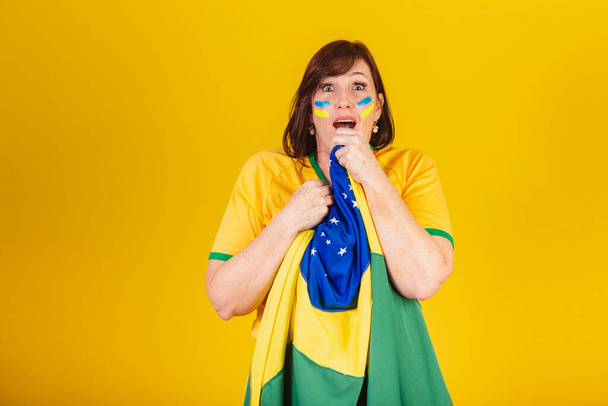 red-haired woman, Brazilian soccer fan. fluttering with the flag of Brazil, surprised. - Valokuva, kuva