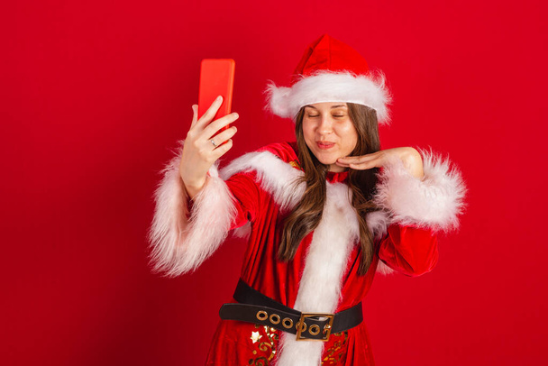 Caucasian, Brazilian woman in Christmas clothes, Santa Claus. self portrait by smartphone. - Φωτογραφία, εικόνα
