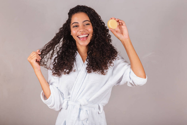 Brazilian black woman, wearing bathrobe and towel. vegan products for beauty and skin and hair care. soaps, Spa, self care. welfare. - 写真・画像