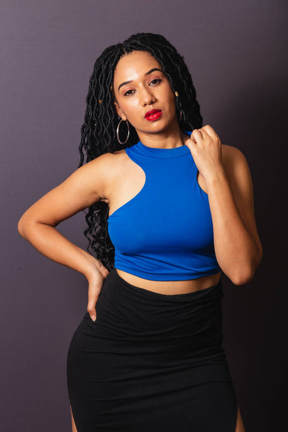 Beautiful black Brazilian woman, dressed in blue. Half body portrait, gray infinity background. - 写真・画像