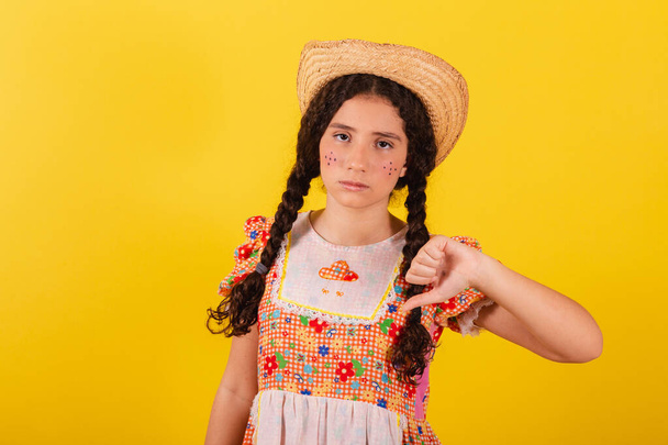 Girl wearing traditional orange clothes for festa junina. Thumb down, disapproval. bad. - Foto, immagini