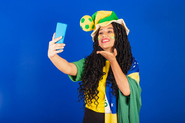 Young black Brazilian, soccer fan. making self portrait in selfie, smartphone. - Фото, зображення
