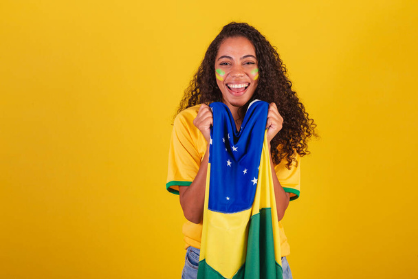 Young black Brazilian woman, soccer fan. with brazil flag. vibrating smiling - Photo, Image