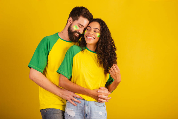 couple of brazil soccer supporters, dressed in the colors of the nation, black woman, caucasian man. together, romantic - Photo, Image