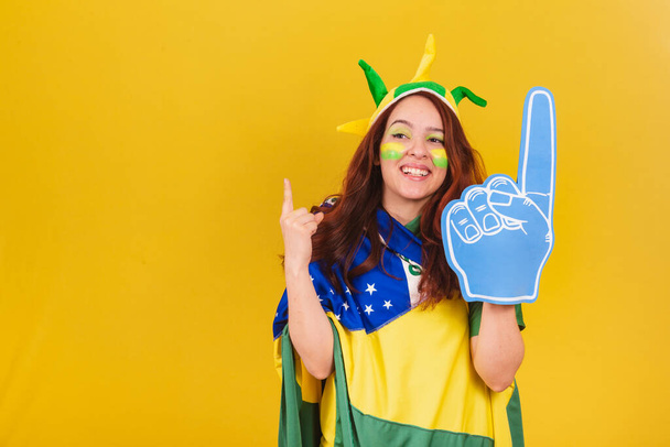 caucasian woman, redhead, soccer fan from Brazil, using foam finger, cheering, coleographed dance. - Photo, Image