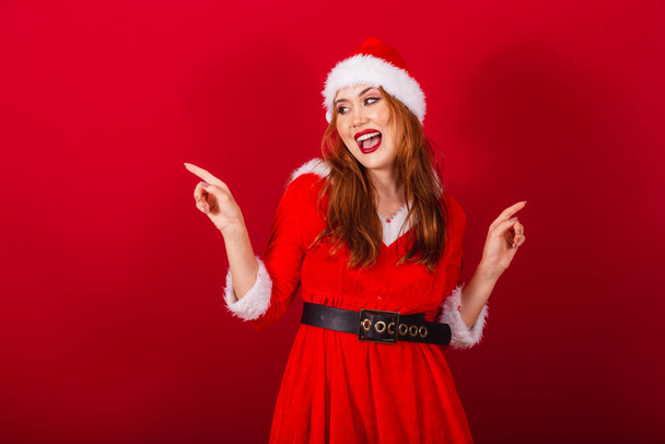 beautiful Brazilian red-haired woman, dressed in Christmas clothes, Santa Claus. dancing. - Foto, Imagen