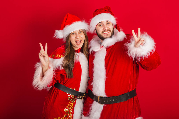brazilian couple with christmas clothes, santa claus. sign of peace and love. - Foto, Imagem