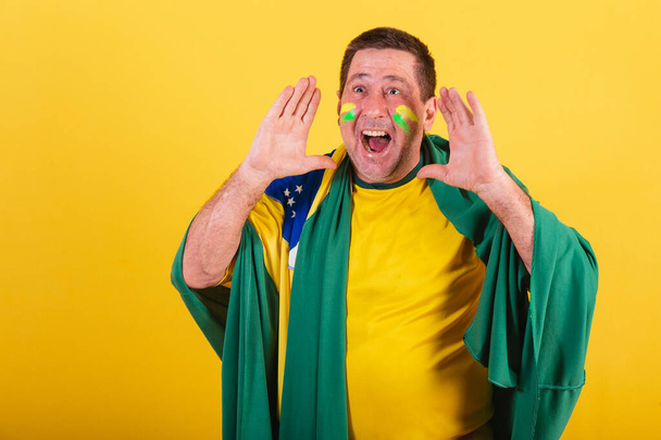 adult man, soccer fan from brazil, using flag, shouting promotion. advertising photo. - Foto, afbeelding