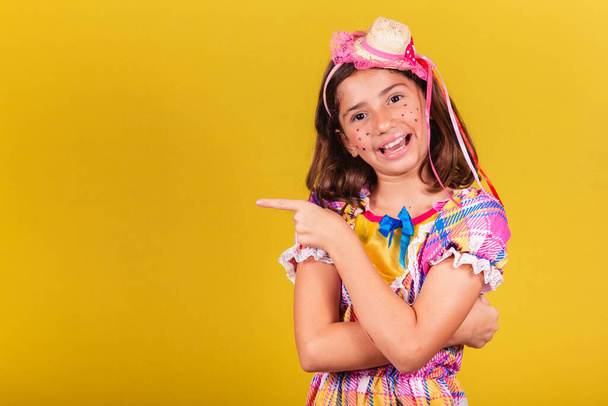 brazilian, caucasian child, festa junina clothes, pointing with finger to negative space, text, advertisement, advertisement. May, June and July festivities, festa junina celebrations - 写真・画像
