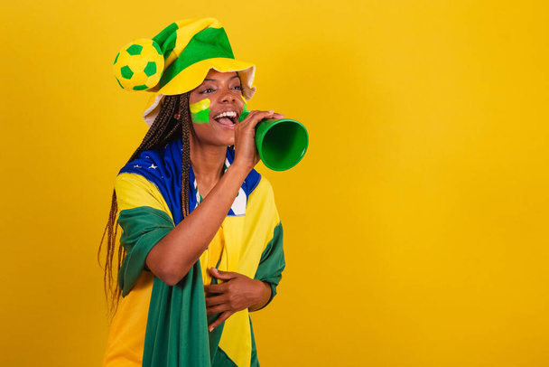 black woman young brazilian soccer fan. using phone pick up to announce something. - Foto, Imagen