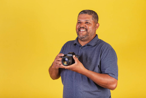 Brazilian black man, adult holding photo camera, photography hobby, photographer. - Foto, immagini