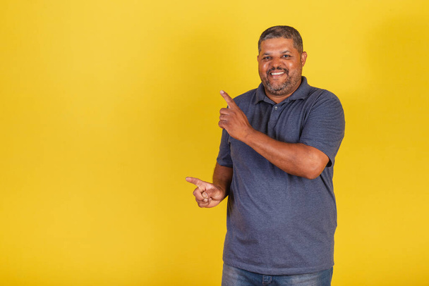Brazilian black man, adult smiling, pointing to the left, publicity photo - 写真・画像
