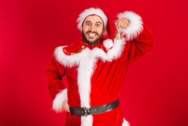 brazilian man, dressed in santa claus clothes, holding christmas bell. - Foto, immagini