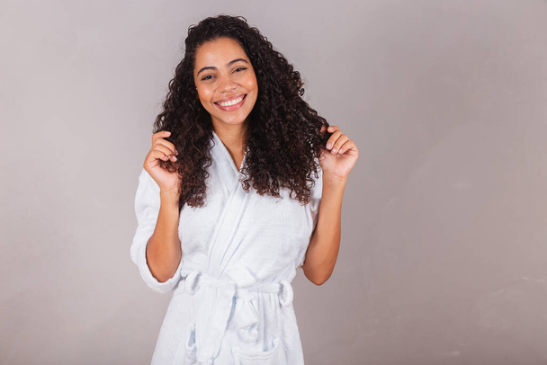 Brazilian black woman, wearing bathrobe and towel. curly hair, spa, beauty center, hair care. showing hair. curls. - Fotografie, Obrázek