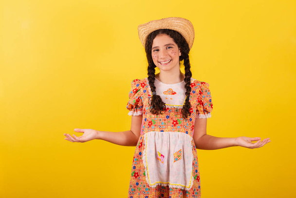 Girl wearing traditional orange clothes for festa junina. With open arms, welcome, welcoming. - Fotó, kép