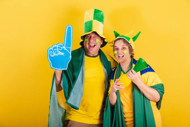 adult couple, soccer fan from brazil, wearing flag and hat. Cheering and partying. - Photo, Image