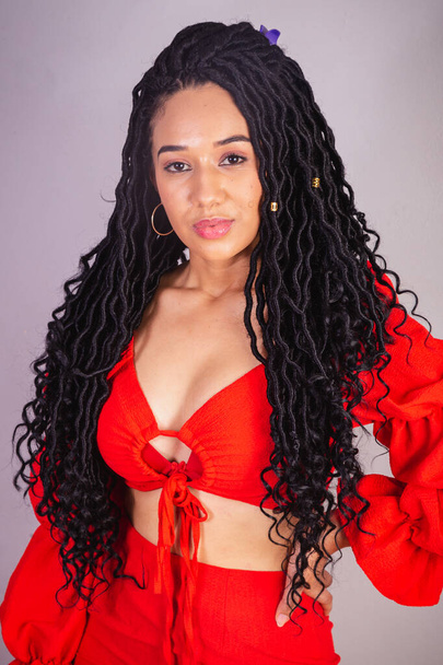 Beautiful black Brazilian woman, dressed in red. with your hands on your hips. - Foto, Bild
