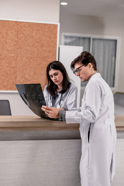 Physician and radiologist analyze medical images, including MRI film, to identify patient condition in order to develop treatment plans and future medical procedures, refer patients to specialists. - Foto, afbeelding