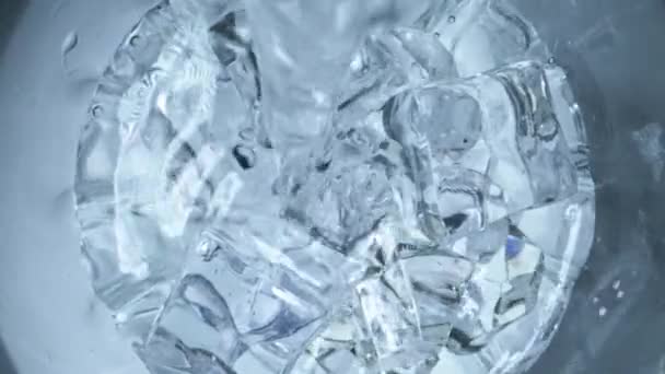 Water wordt in een glas met ijs gegoten. - Video