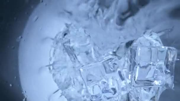Water wordt in een glas met ijs gegoten. - Video