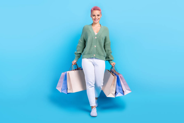 Full body cadre of satisfied stylish wear model promoter beautiful woman with bags from new yorker store isolated on blue color background. - Photo, image