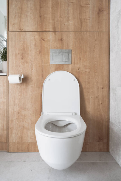 front view of white ceramic wc bowl with open lid in luxury bathroom interior. apartment toilet with concealed cistern integrated in wall - 写真・画像
