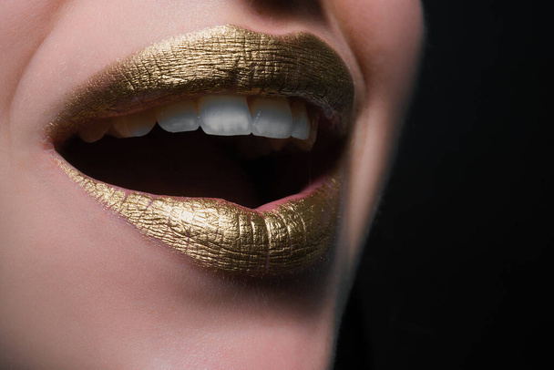 Smiling lips. Closeup sexy beautiful female golden lips isolated. Gold lipstick - Φωτογραφία, εικόνα