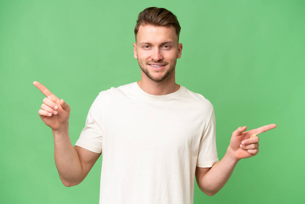 Молода блондинка білий чоловік над ізольованим тлом вказує палець на латералів і щасливий
 - Фото, зображення