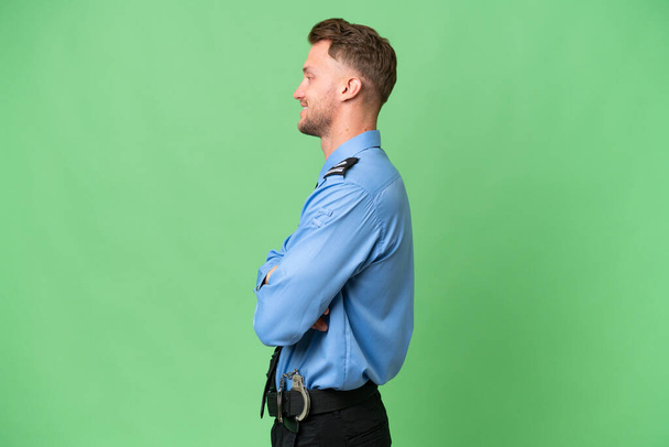 Young police man over isolated background in lateral position - Photo, image