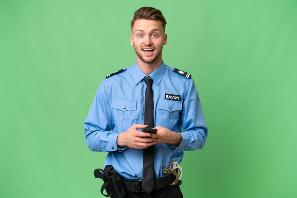 Giovane poliziotto su sfondo isolato sorpreso e l'invio di un messaggio - Foto, immagini
