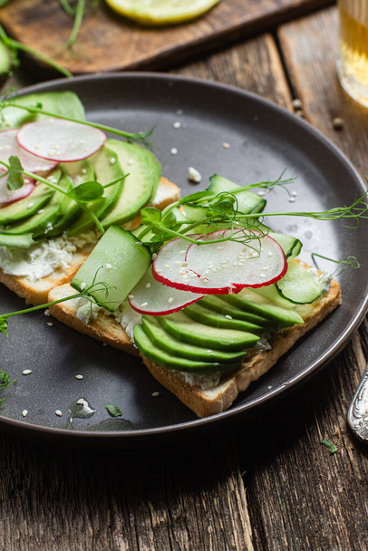 White bread toasts with cream cheese, avocado, cucumber and radish in a plate - Foto, Bild