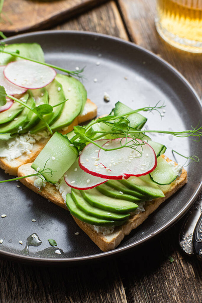 White bread toasts with cream cheese, avocado, cucumber and radish in a plate - Foto, immagini