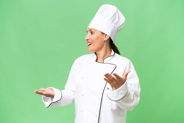 Mujer chef de mediana edad sobre fondo aislado con expresión facial sorpresa - Foto, imagen