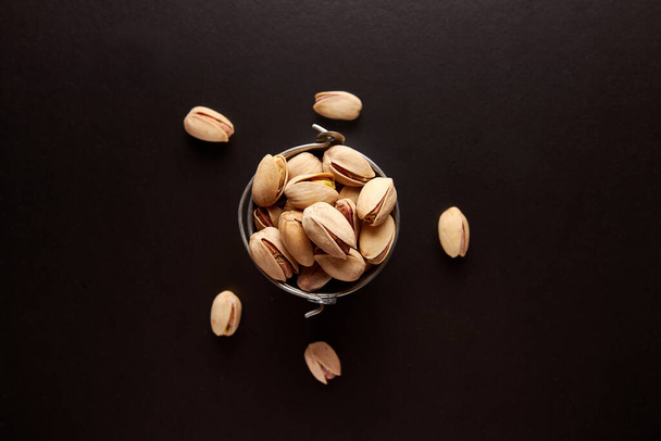 Pistachios in a small metal bucket on a black background. - Photo, image