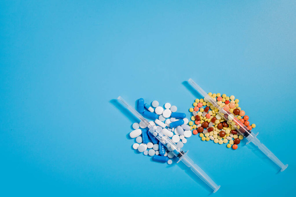Two medical syringes with pills and randomly scattered pills of different colors and sizes. Treatment concept. - Fotoğraf, Görsel