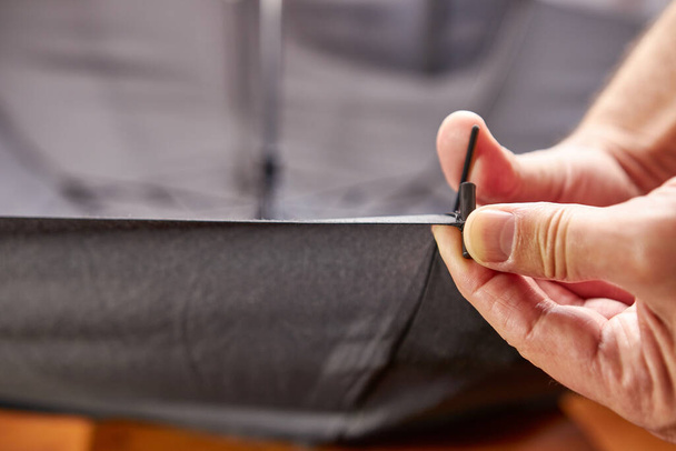 Un artesano repara un paraguas cambiando la aguja con una herramienta de mano. Pequeña reparación de artículos para el hogar. - Foto, Imagen