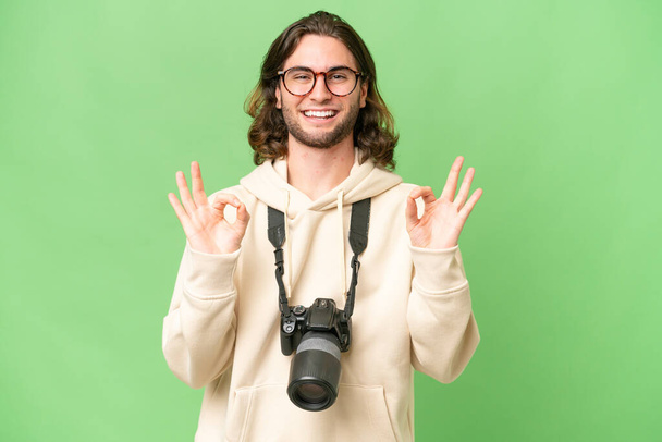 Jovem fotógrafo homem sobre fundo isolado mostrando um sinal ok com os dedos - Foto, Imagem