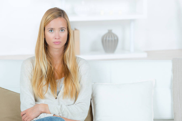 serious young woman sat at home on the sofa - Photo, Image