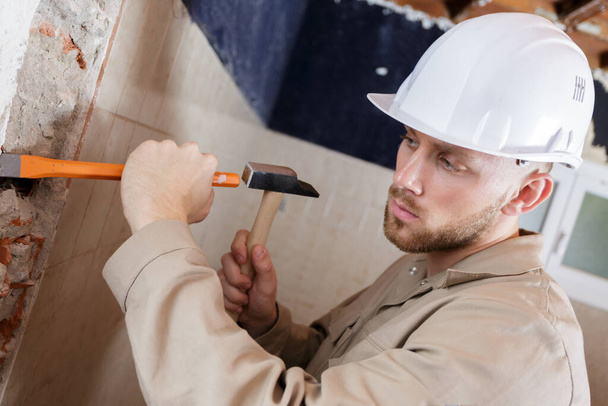 young male contractor using hammer and chisel - Foto, immagini