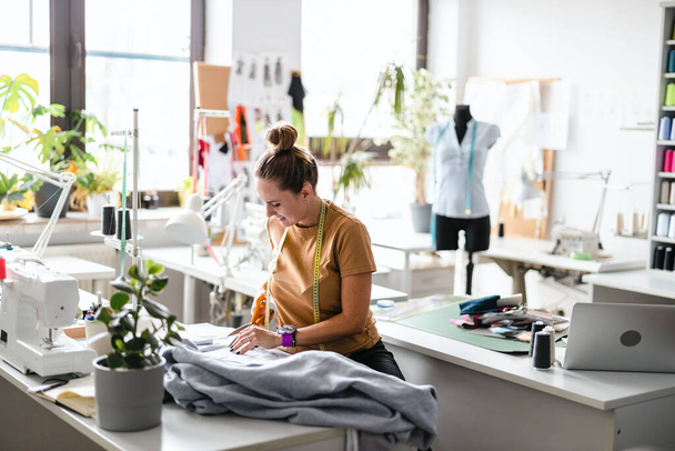 Young fashion designer working at her workplace - 写真・画像